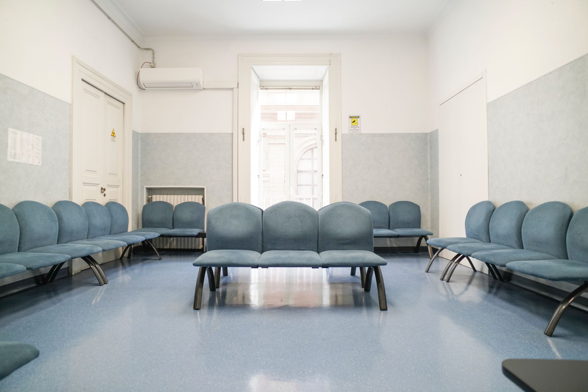 Una sala d'attesa vuota con sedie blu e un tavolo.