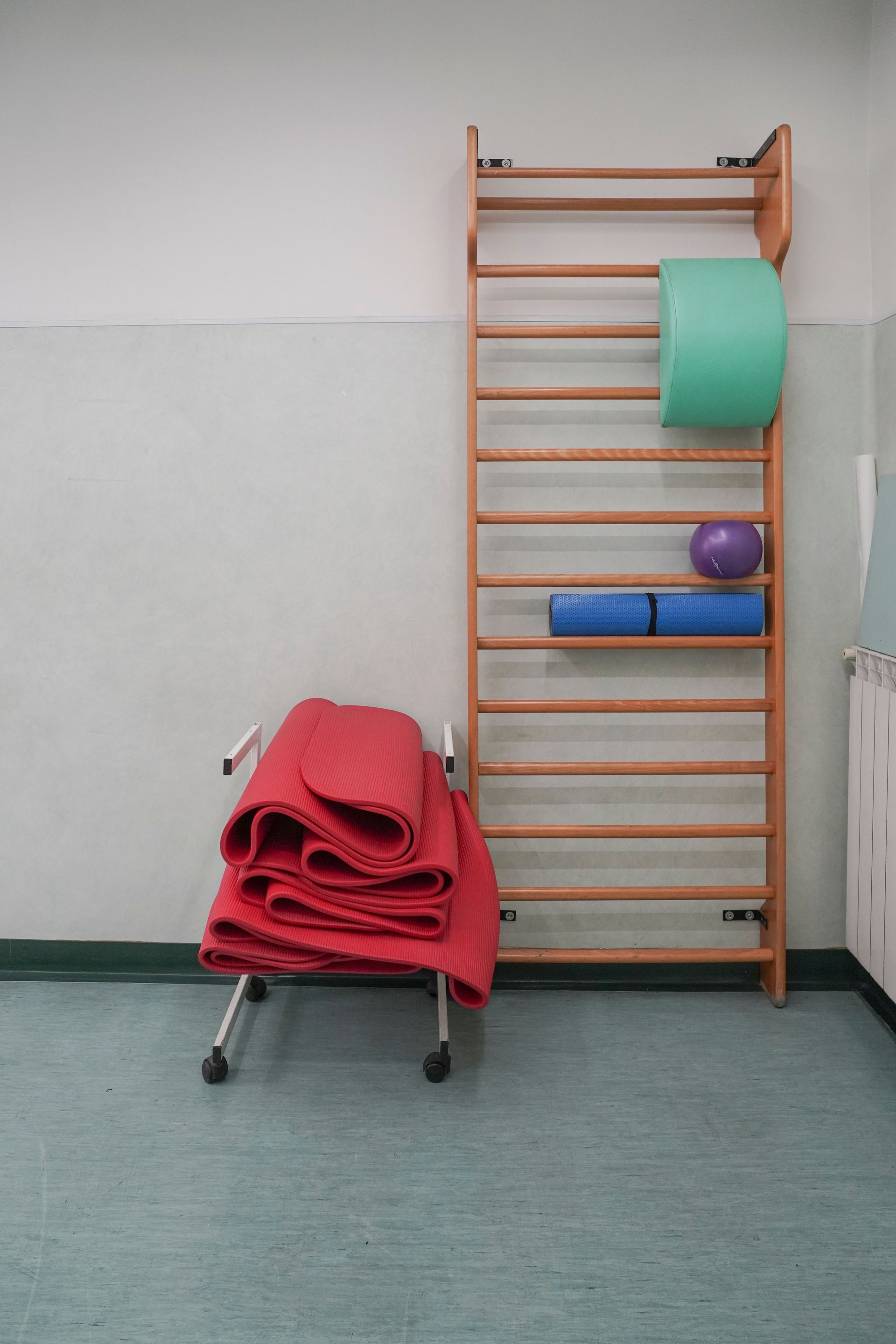 Una palestra con un muro svedese e una pila di materassini