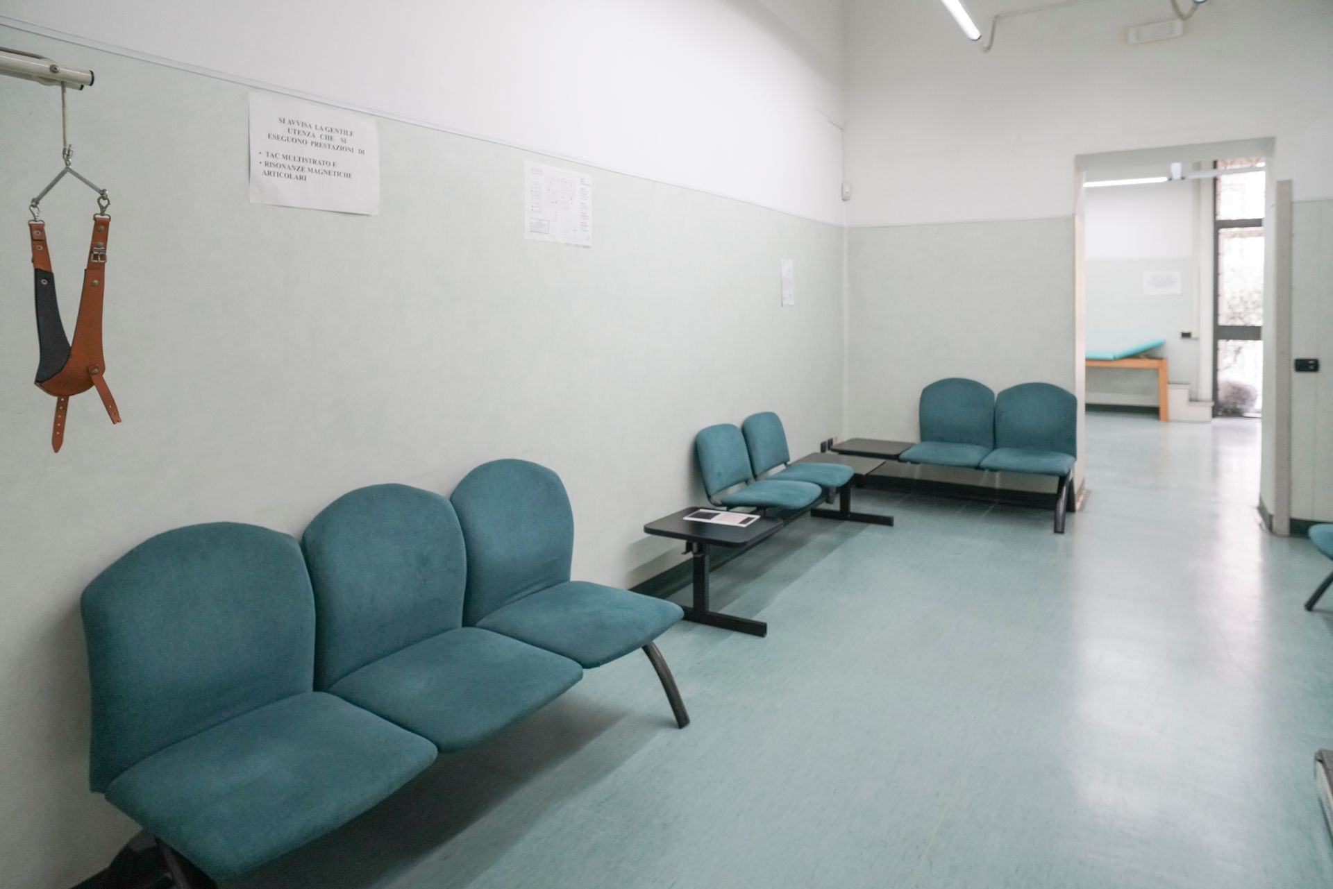 Una sala d'attesa con sedie blu e un cartello sul muro