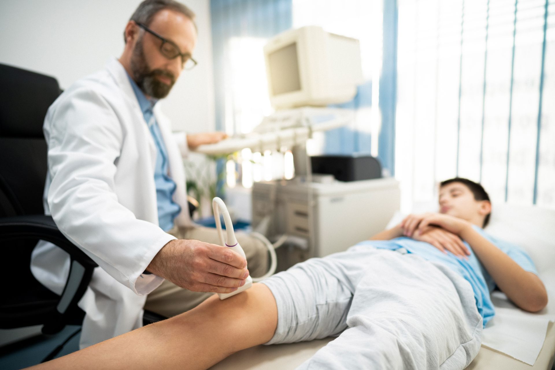 Un medico sta esaminando la gamba di un paziente con un apparecchio a ultrasuoni.