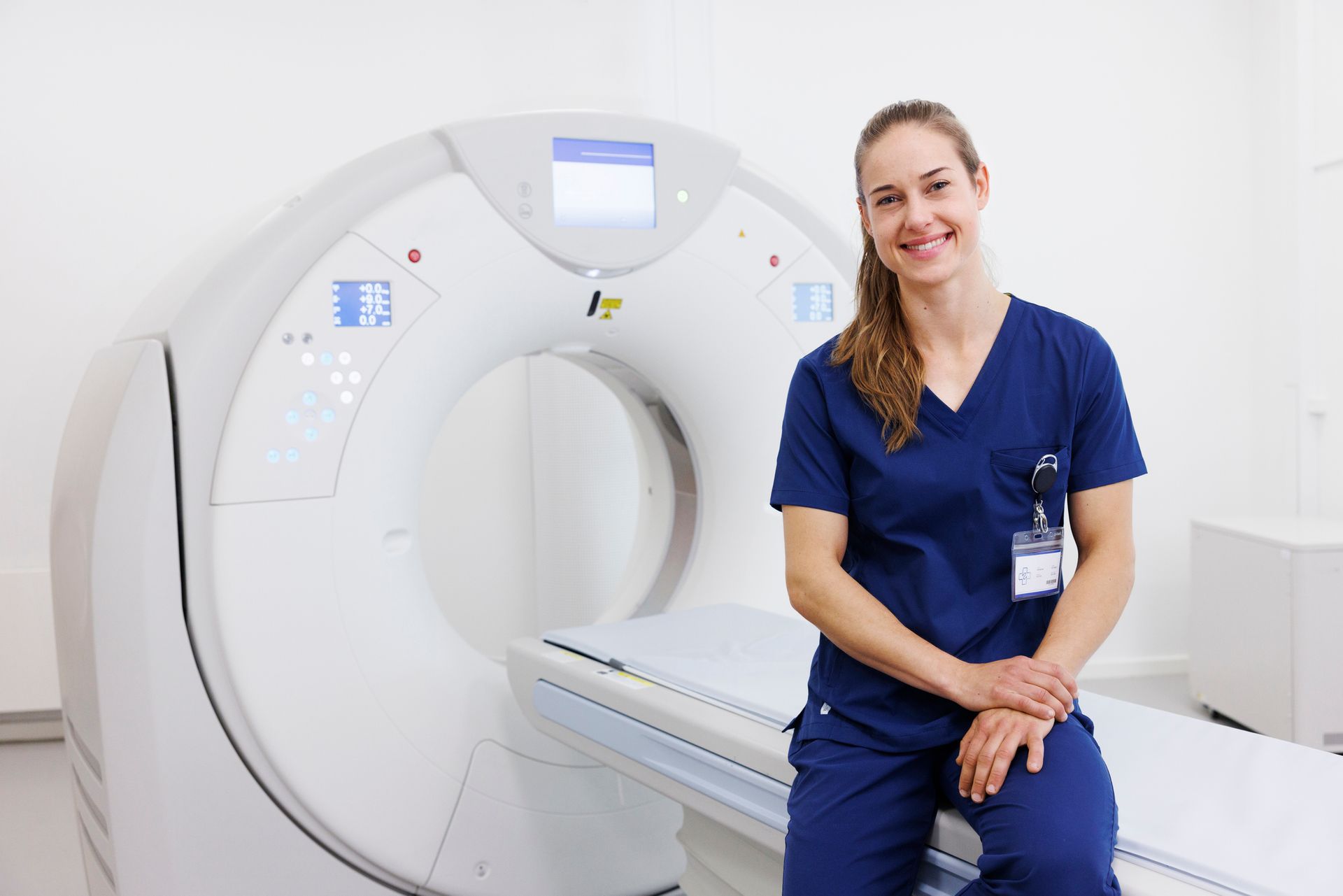 Un'infermiera è seduta davanti a una macchina per la TAC.