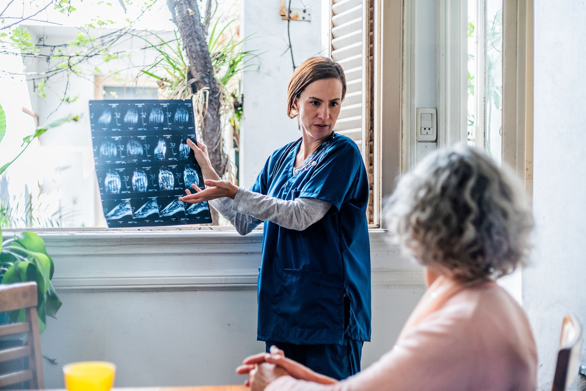 Un'infermiera mostra una radiografia a una donna anziana.
