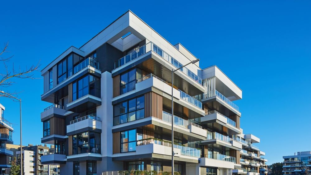 Modern apartment building with white and brown exterior against a blue sky.