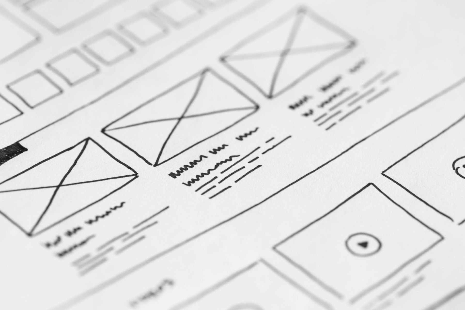 Wireframe sketches of a website layout on paper, illustrating boxes and content placement.