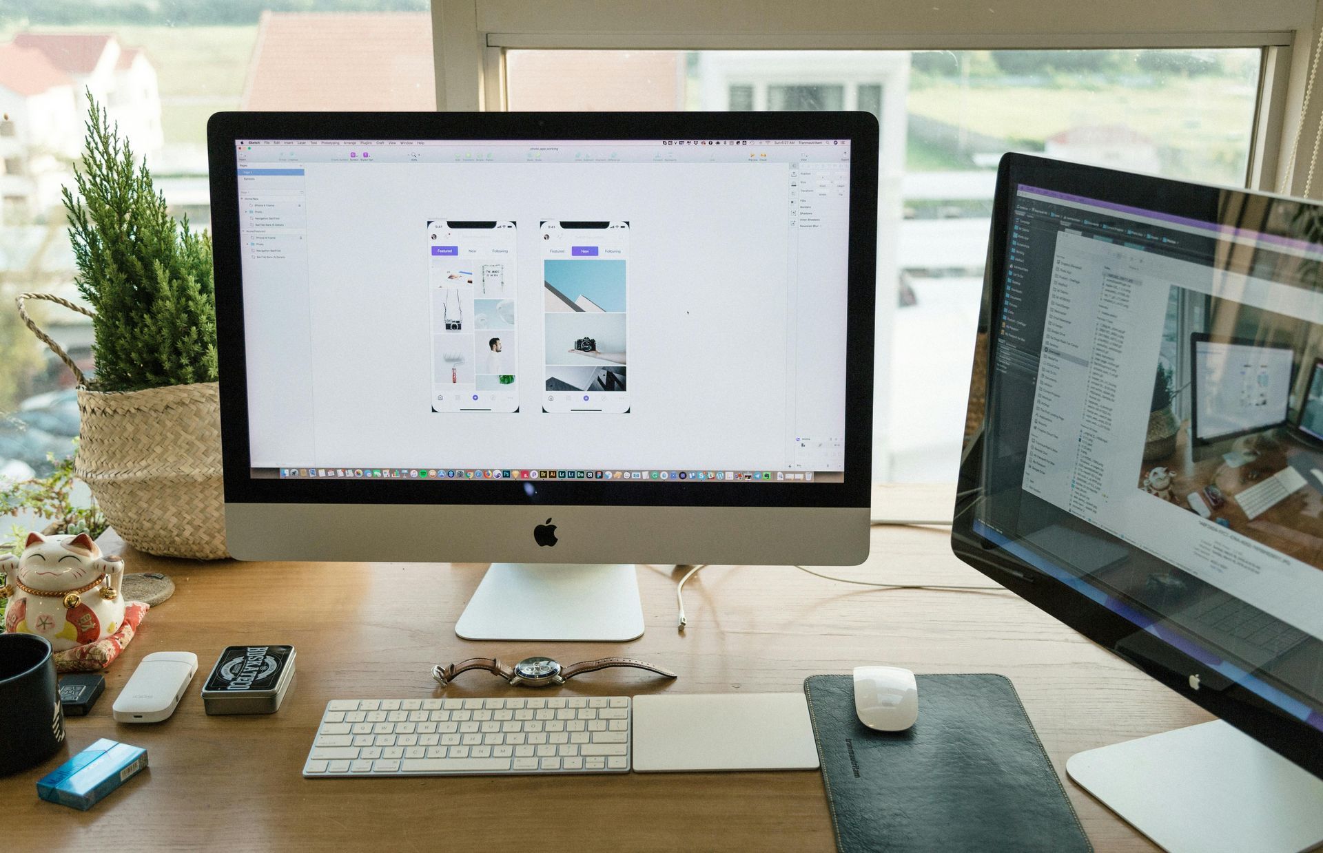 Two computer monitors on a desk. One displays a design interface, the other an image. Keyboard, mouse.