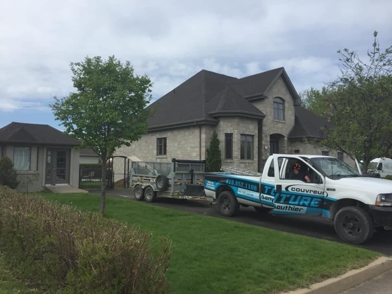 Un camion blanc est garé devant une grande maison.