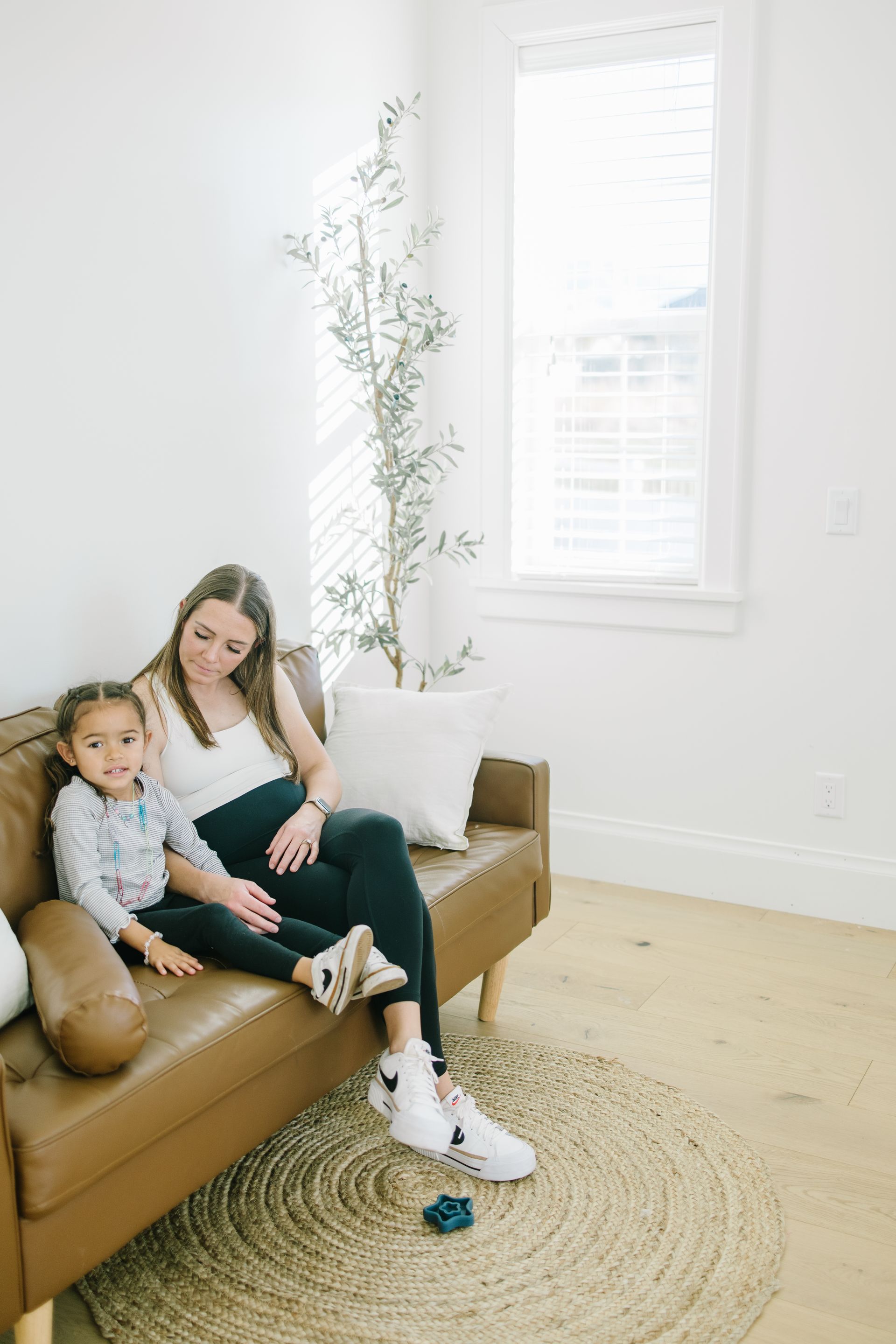 A woman and a child are sitting on a couch in a living room.