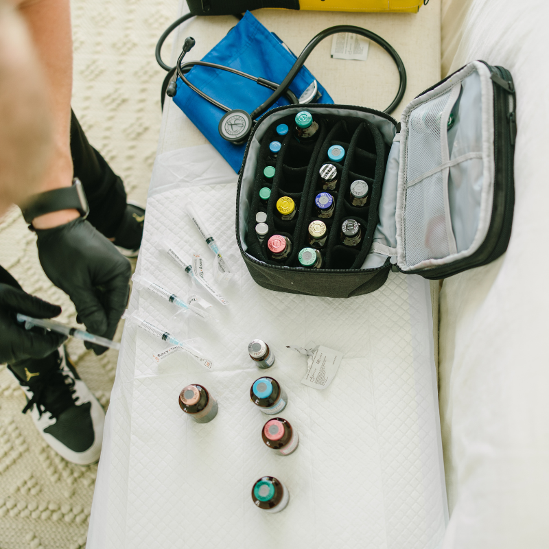 A person is holding a syringe next to a bag filled with bottles