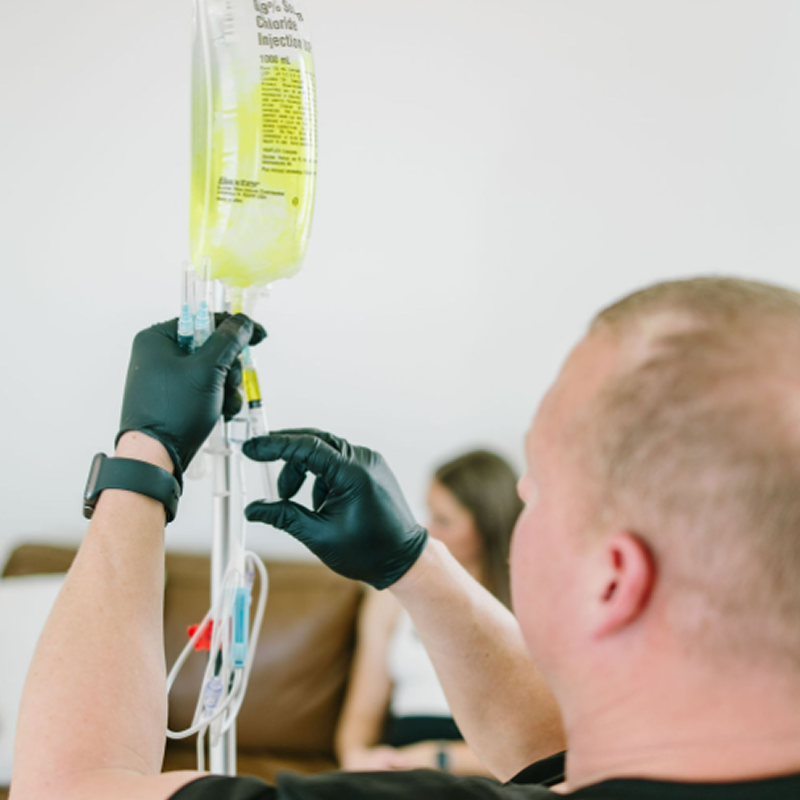 A person is holding a syringe next to a bag filled with bottles