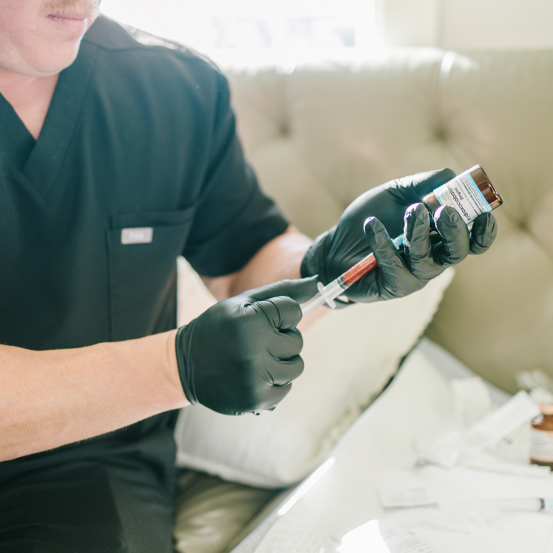 A person is holding a syringe next to a bag filled with bottles