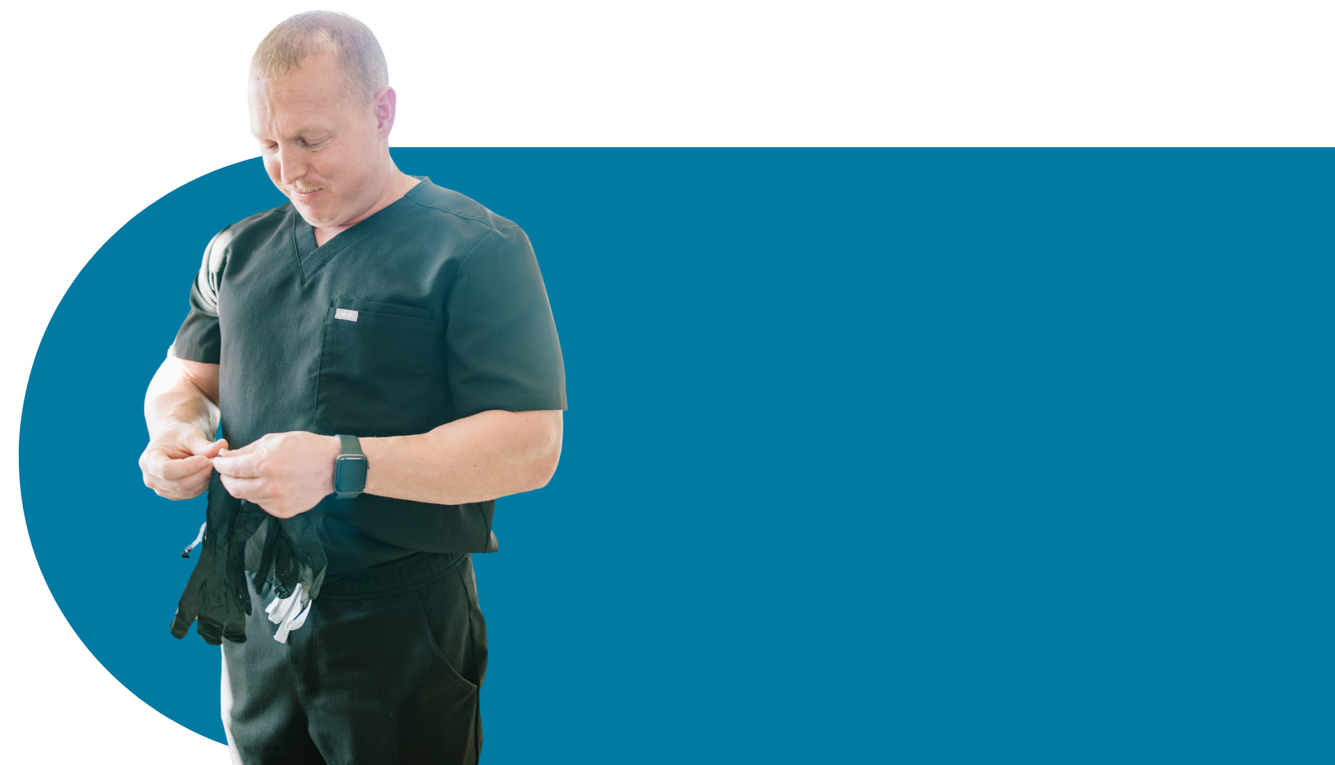 A man in a scrub is standing in front of a blue background.