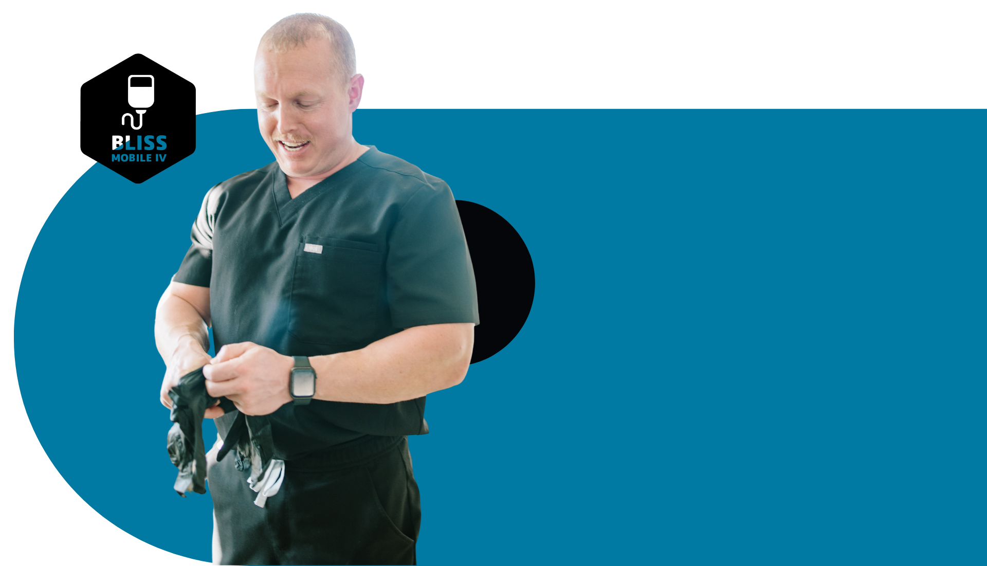 A man in a black scrub top is standing in front of a blue background.