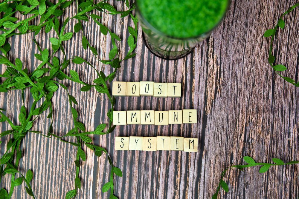 The words boost immune system are written in scrabble tiles on a wooden table.