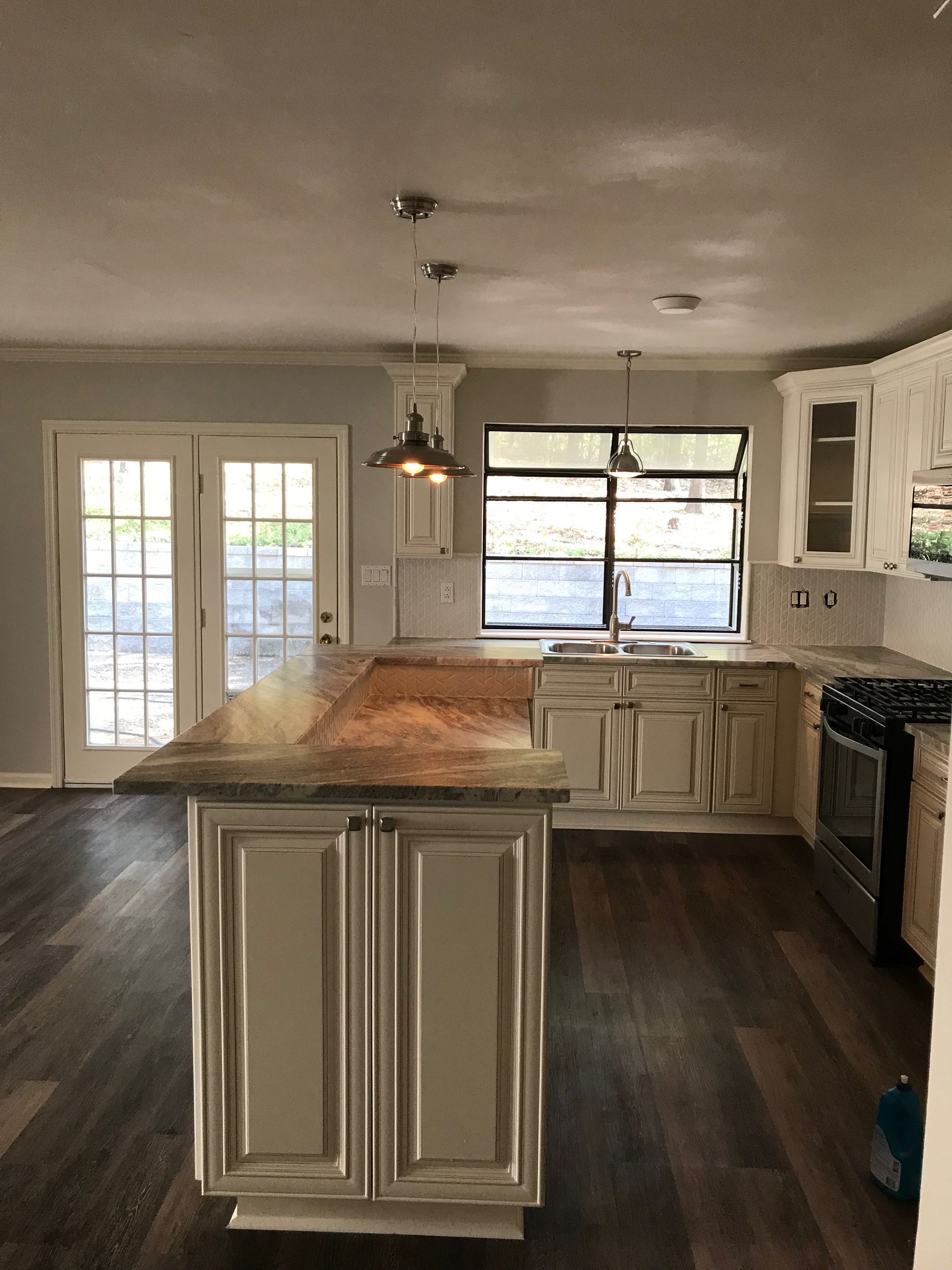 White built-in cabinetry with glass-paned doors and a central double door leading to a room with chairs.