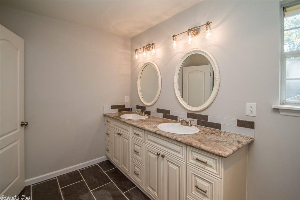 Kitchen with black faucet, sink, and countertop, lit by strip lighting.