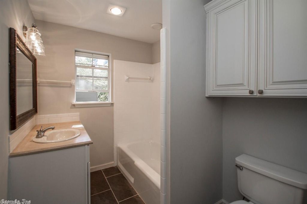 Stack of tiles, bucket of grout, and paintbrush on tiled surface.