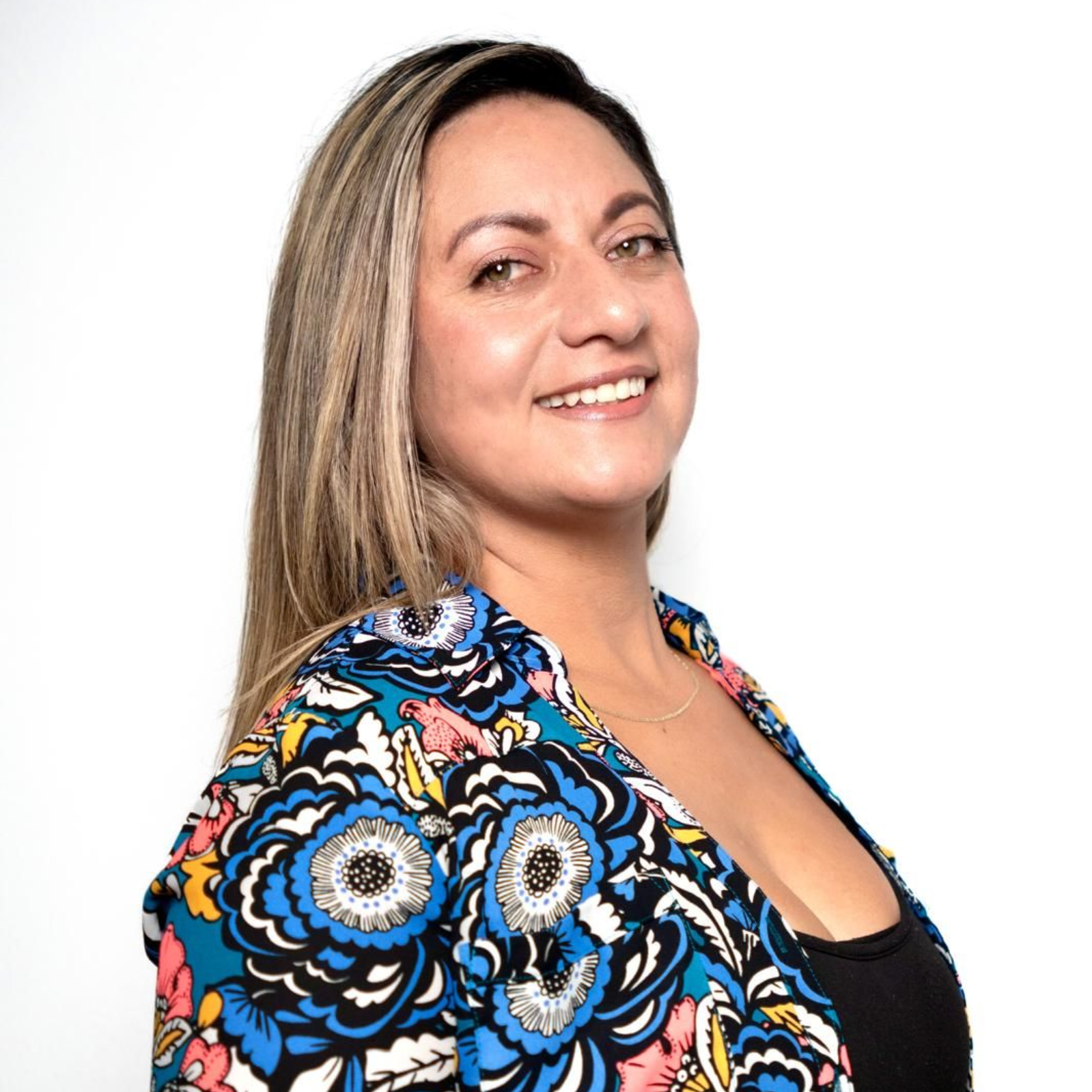 Woman with long brown hair smiling, wearing a black blazer.