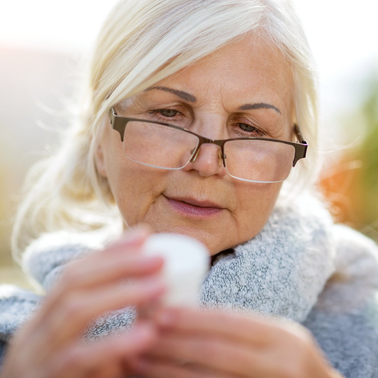Older woman with glasses looking at pill bottle label