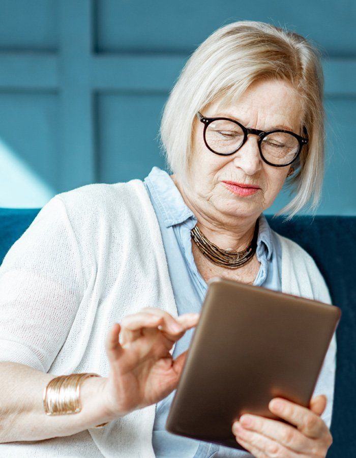 Elderly woman with glasses looking at electronic tablet