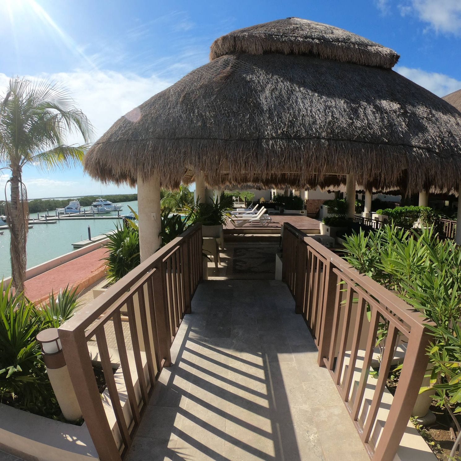Un mirador con techo de paja está rodeado de palmeras.