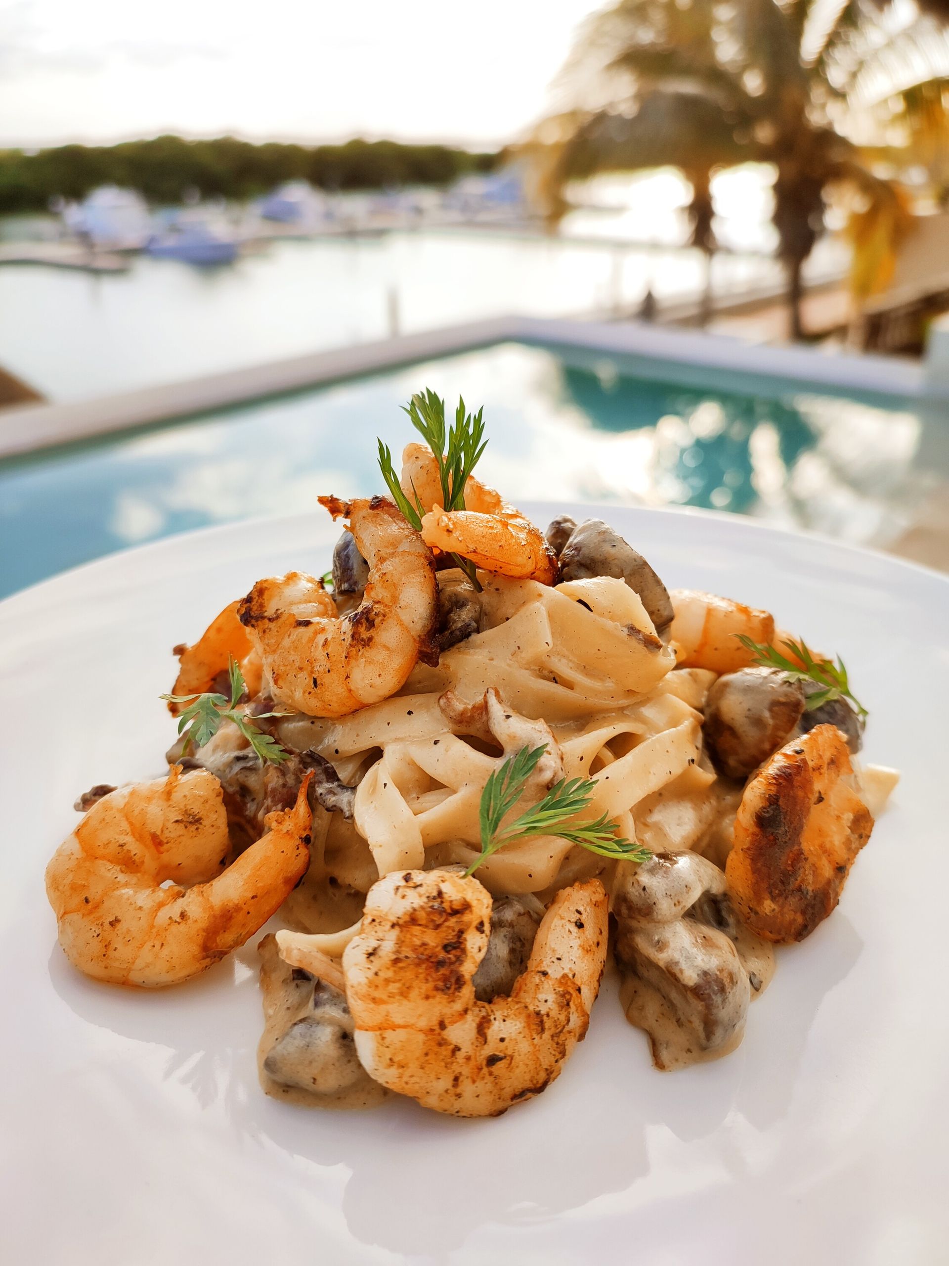 Un plato blanco cubierto con pasta, camarones y champiñones.