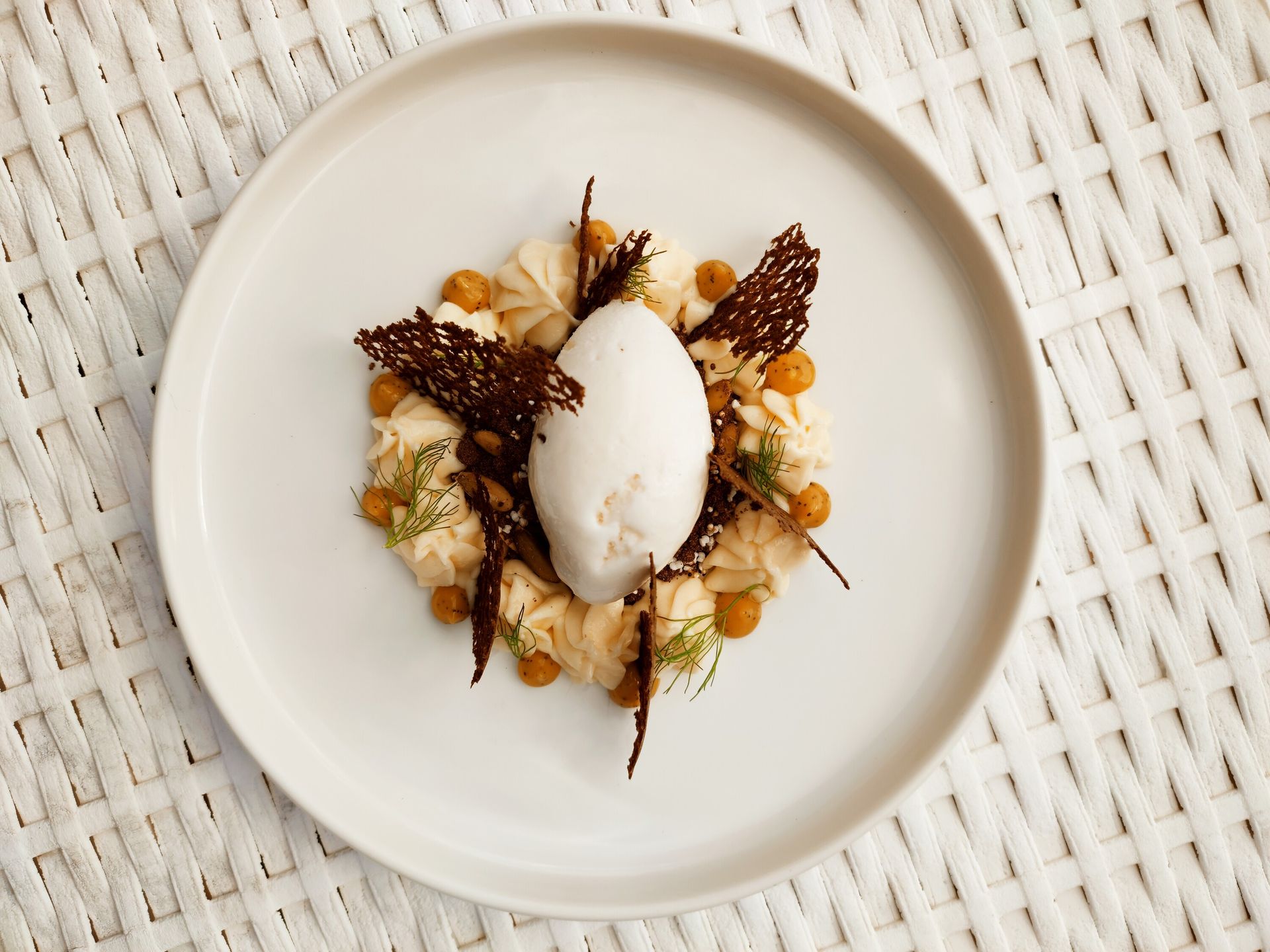 Un plato blanco cubierto con una bola de helado y nueces.