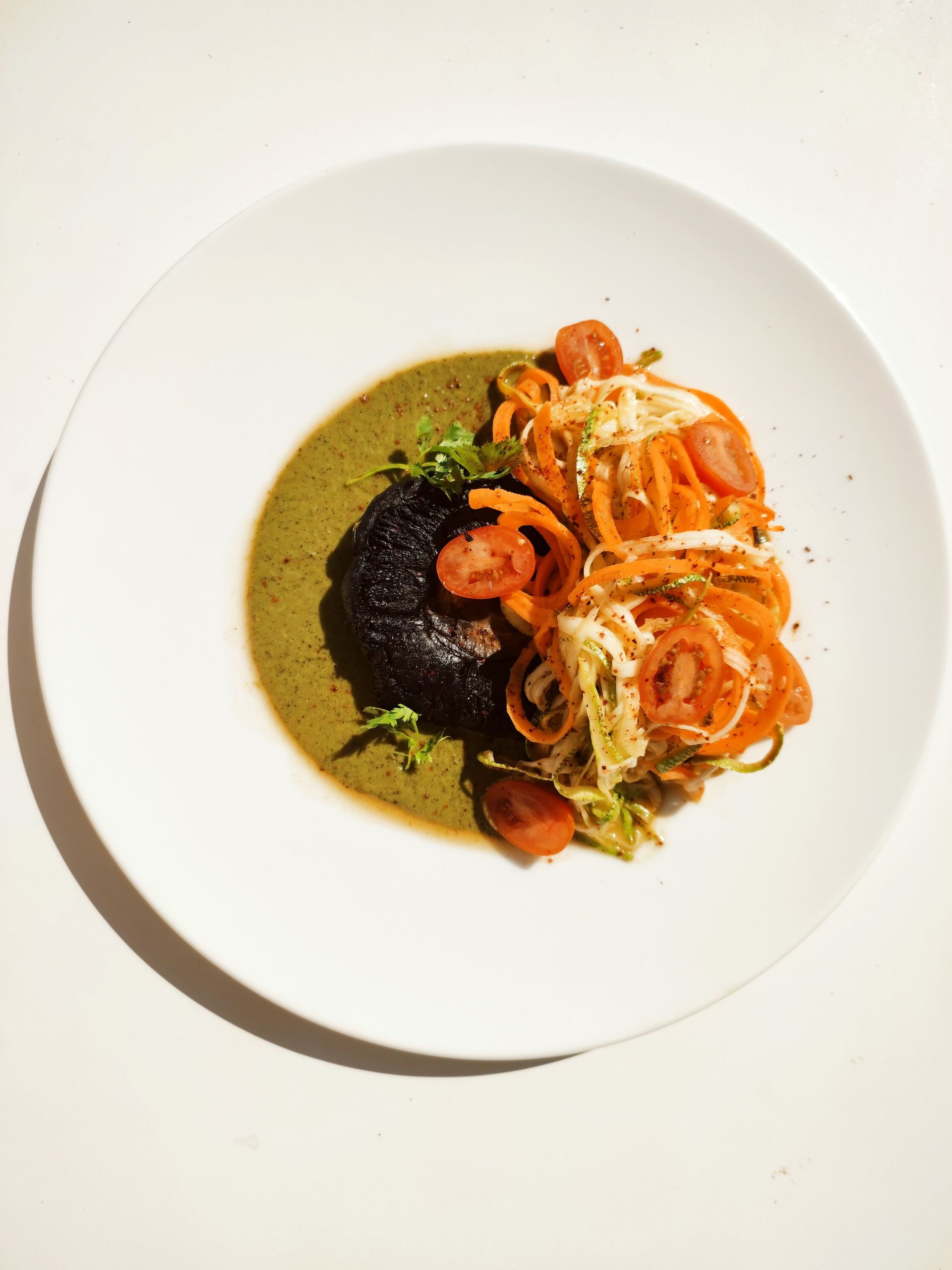 Un plato blanco cubierto con fideos y tomates sobre una mesa.