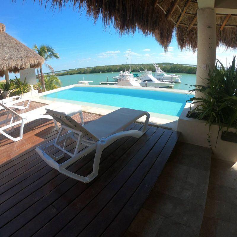 Una terraza con sillas y una piscina al fondo.