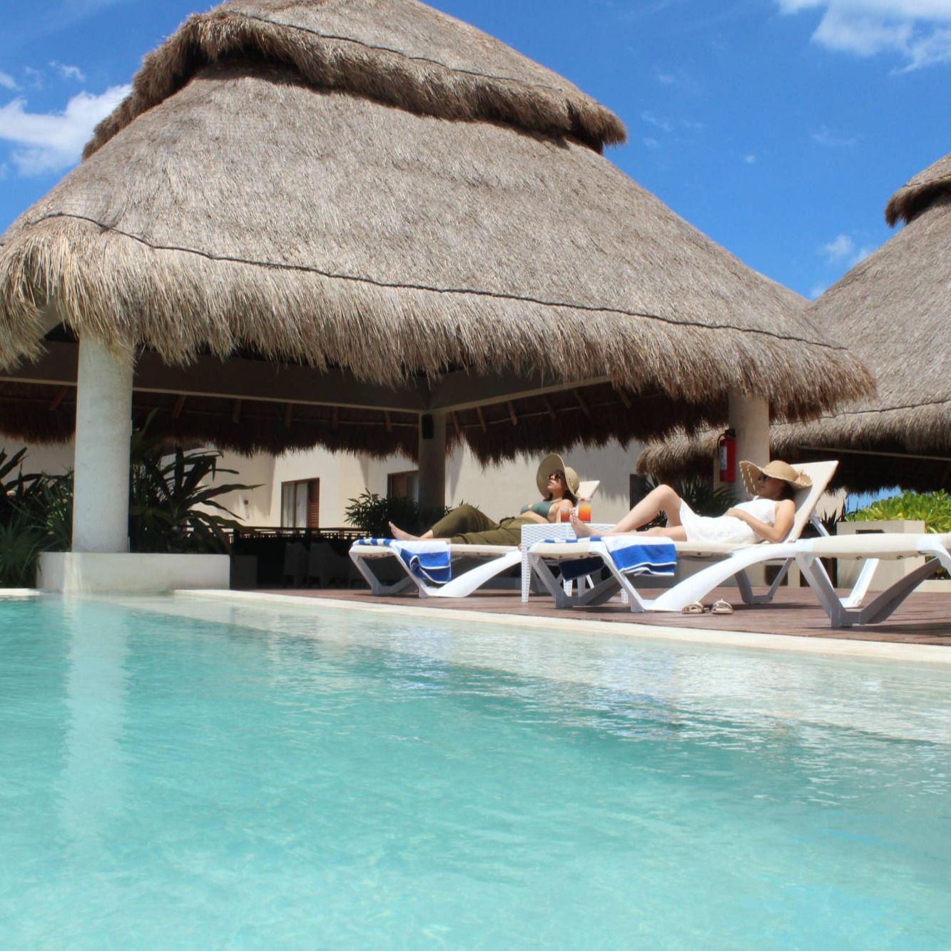 Una mujer se sienta en un sillón cerca de una piscina.