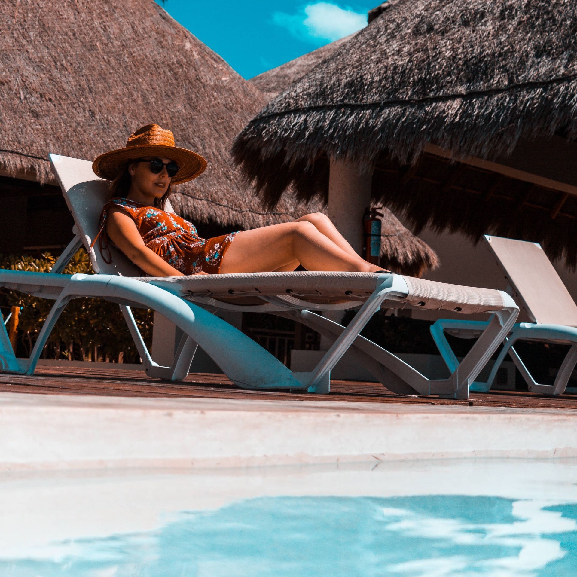 Una mujer está acostada en una tumbona cerca de una piscina.