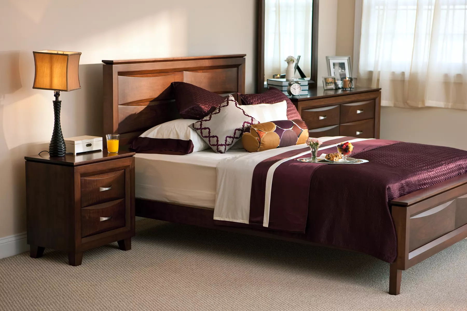 A bedroom with a bed , nightstand , dresser and mirror