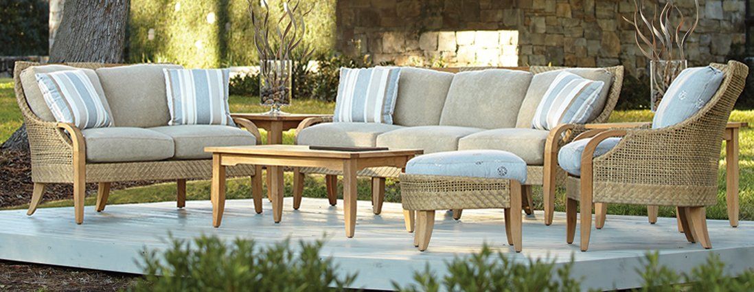 A wicker patio set with a couch , chairs , table and ottoman.