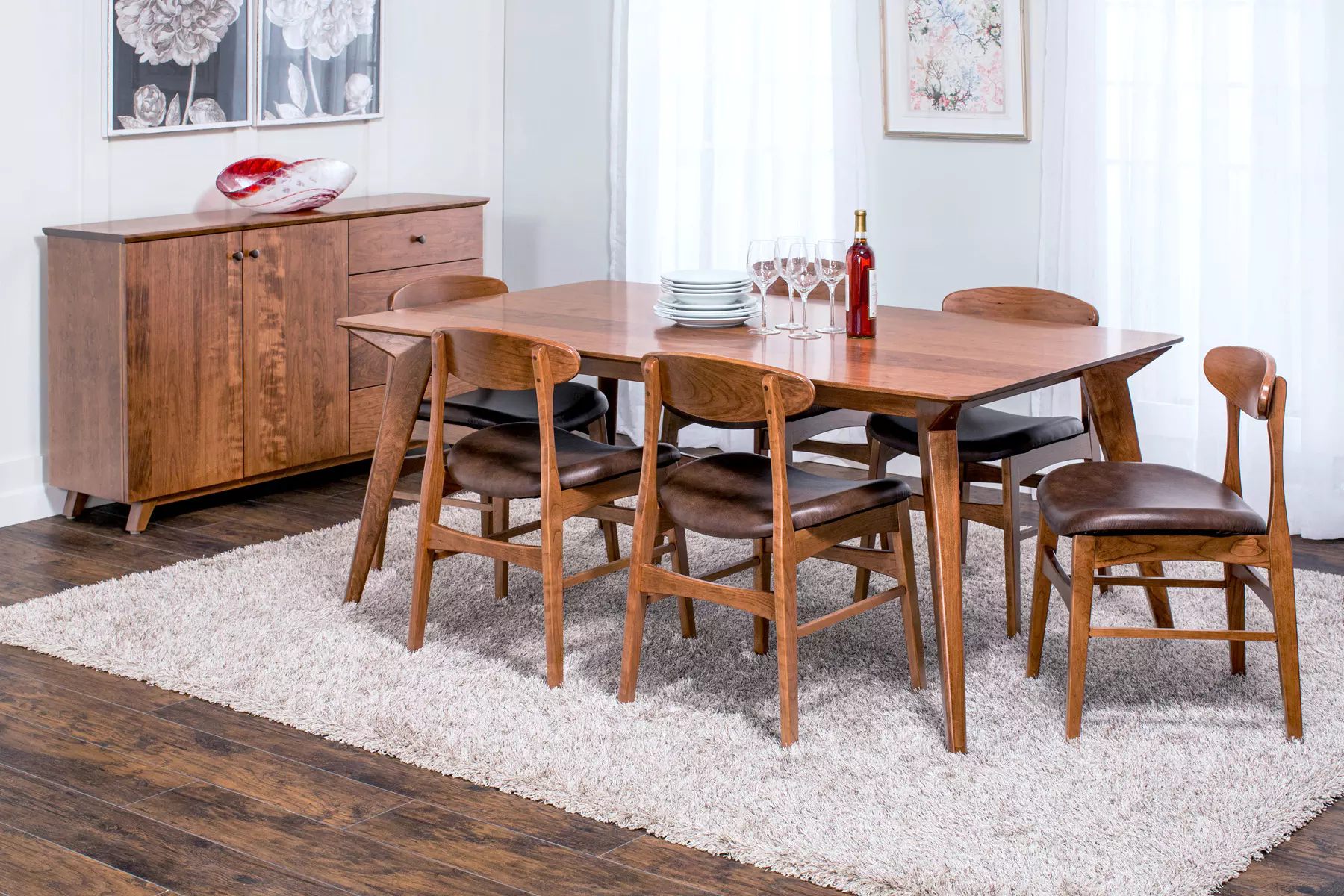 A dining room with a wooden table and chairs and a rug.