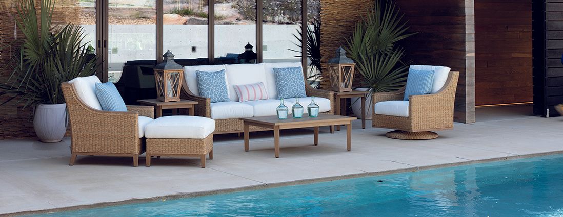 A patio with furniture and a swimming pool in the background.