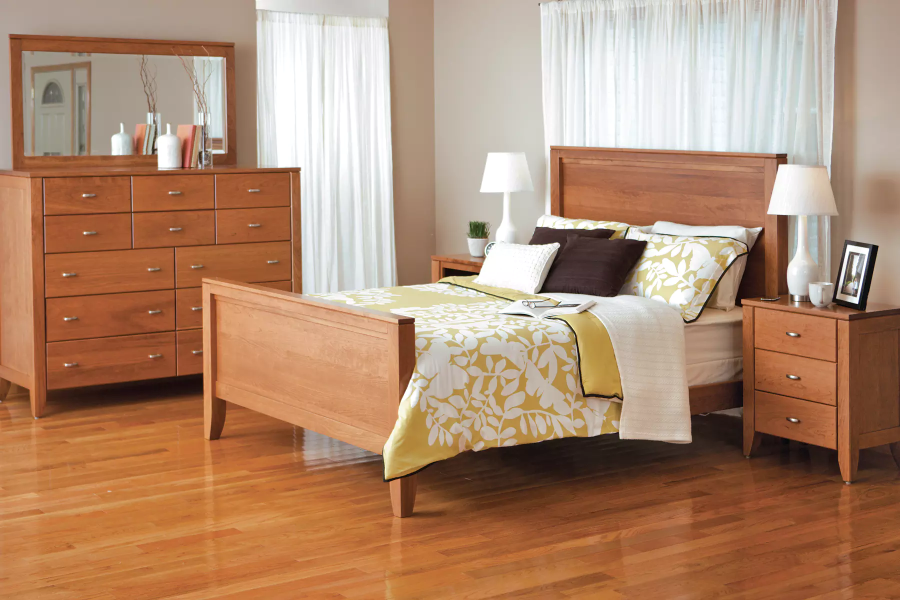 A bedroom with a bed , dresser , nightstand and mirror.