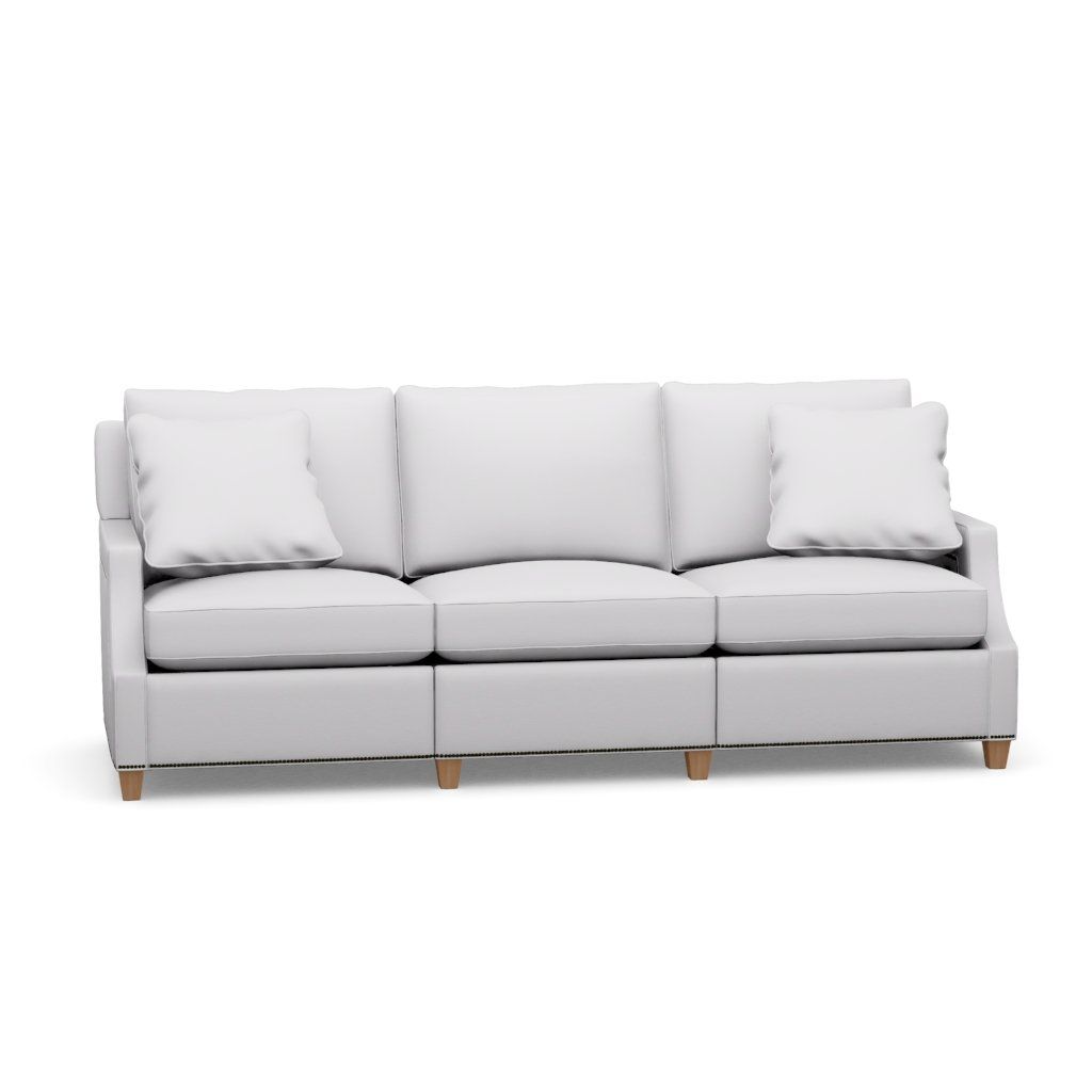 A white couch with wooden legs and pillows on a white background.