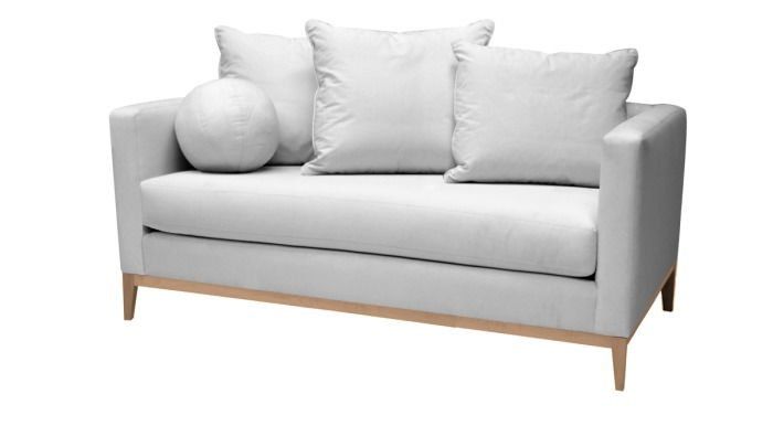 A white couch with three pillows on it