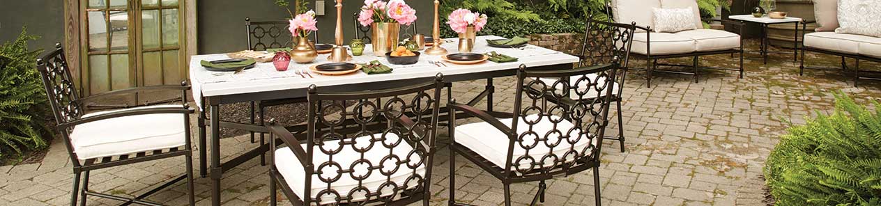 A patio with a table and chairs set up for a dinner party.