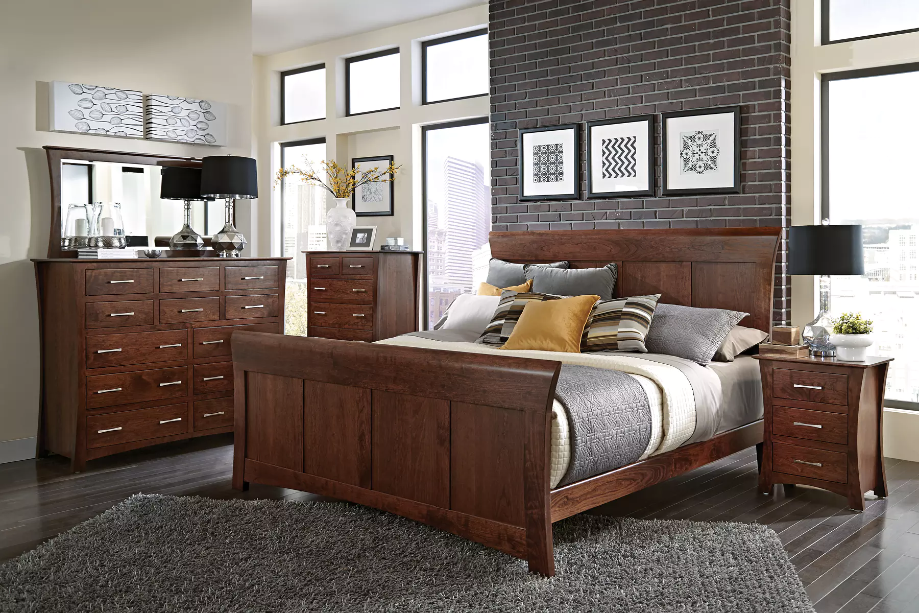 A bedroom with a bed , dresser , nightstand and mirror