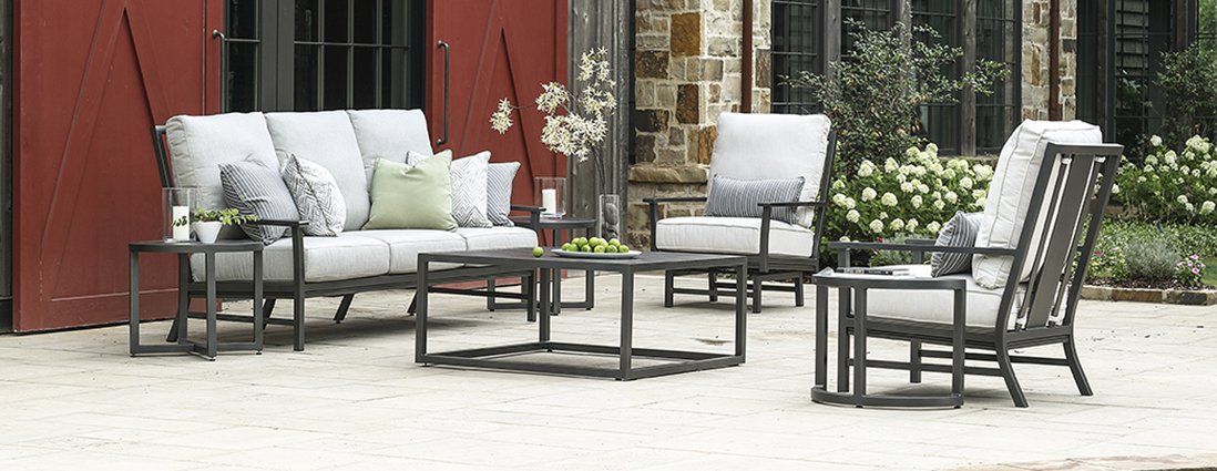 A patio with a couch , chairs , tables and a coffee table.