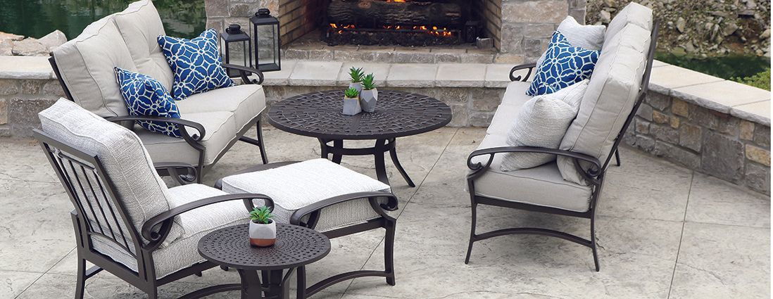 A patio with a couch , chairs , tables and a fireplace.