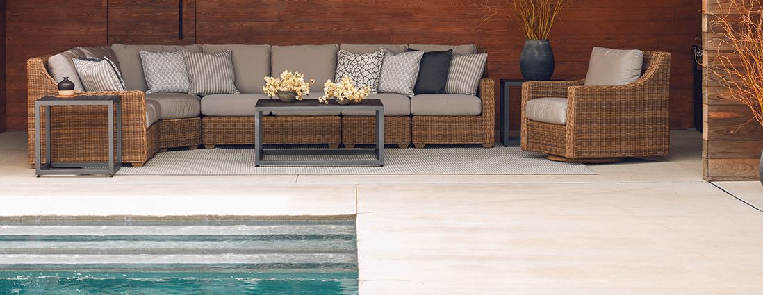A patio with wicker furniture and a swimming pool.