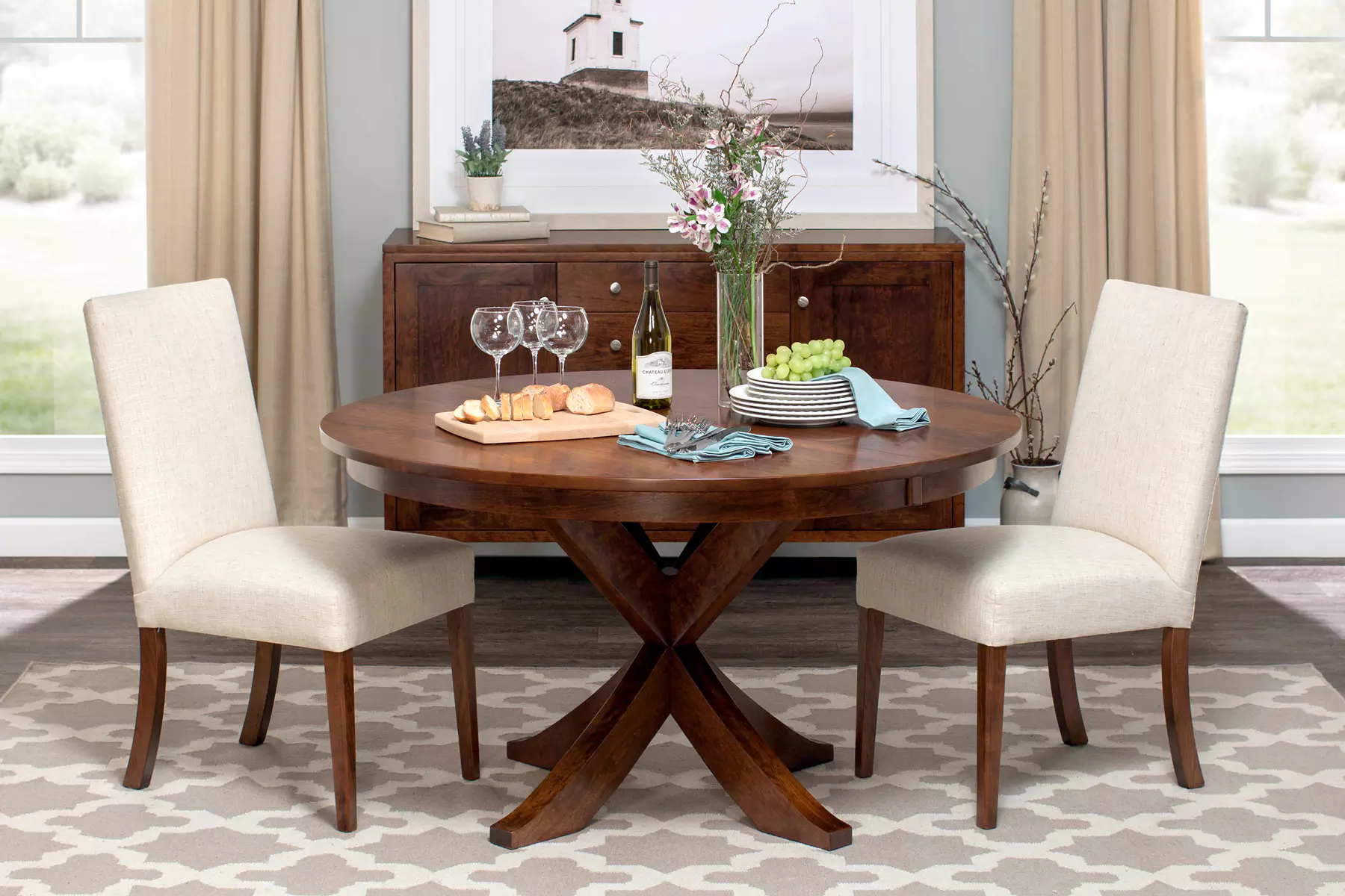 A dining room table with two chairs and a bottle of wine on it.