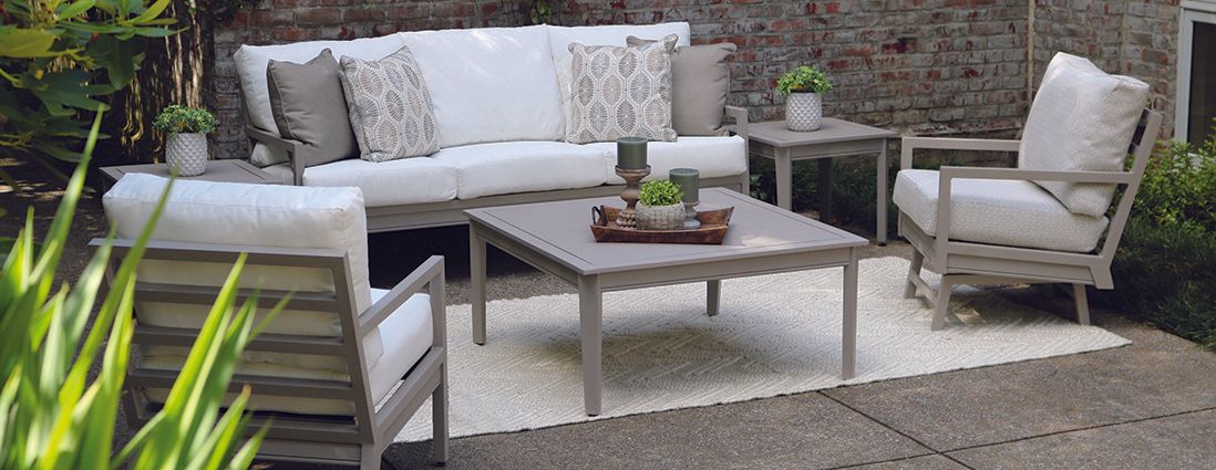 A patio with a couch , chairs , and a coffee table.
