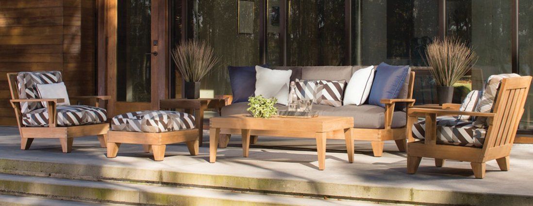 A patio set with a couch , chairs , coffee table and ottoman.