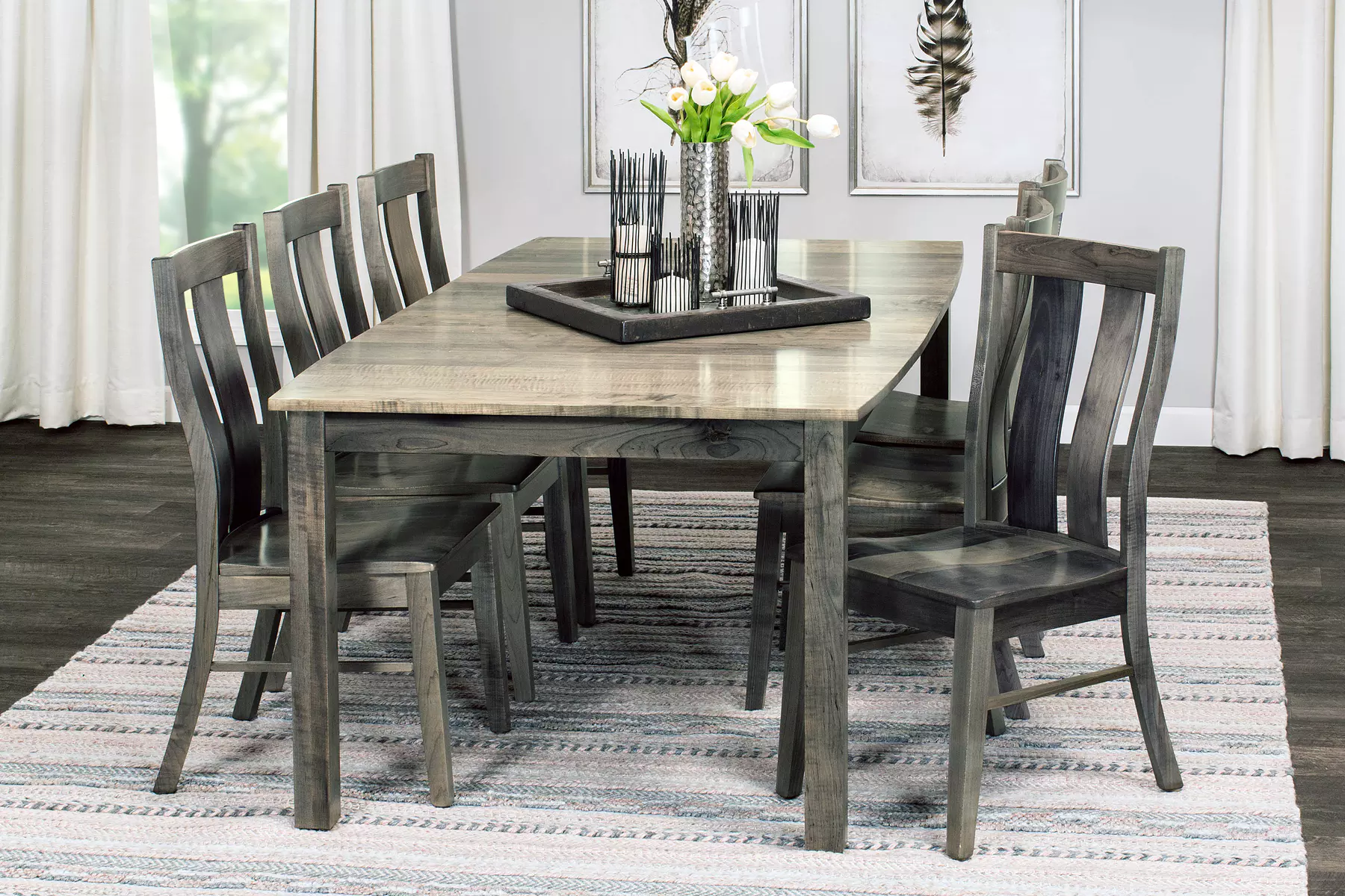 A dining room table and chairs with a vase of flowers on top of it.