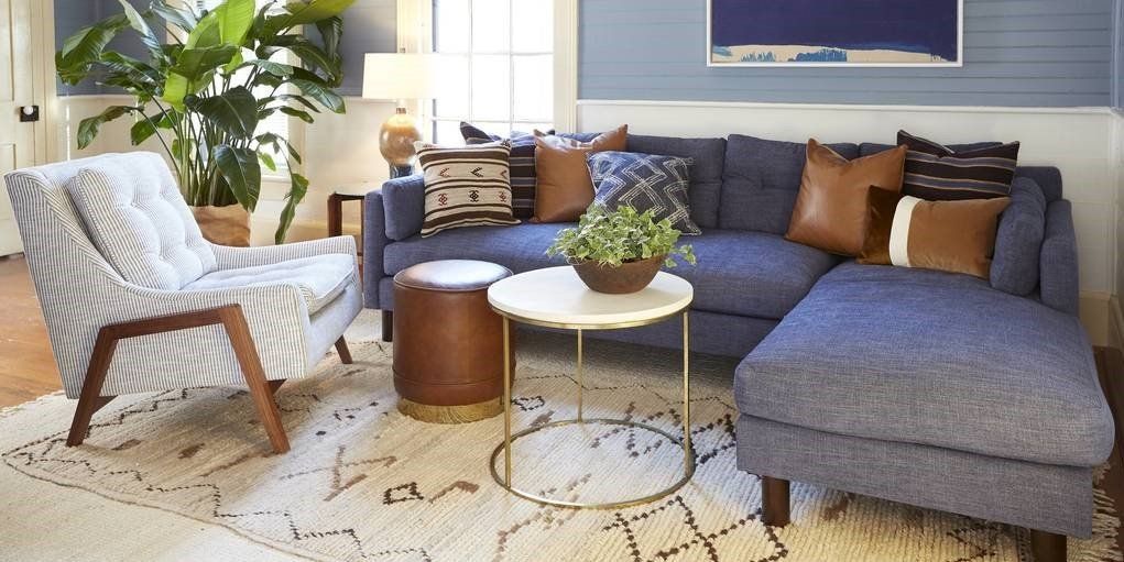 A living room with a couch , chair , table and rug.