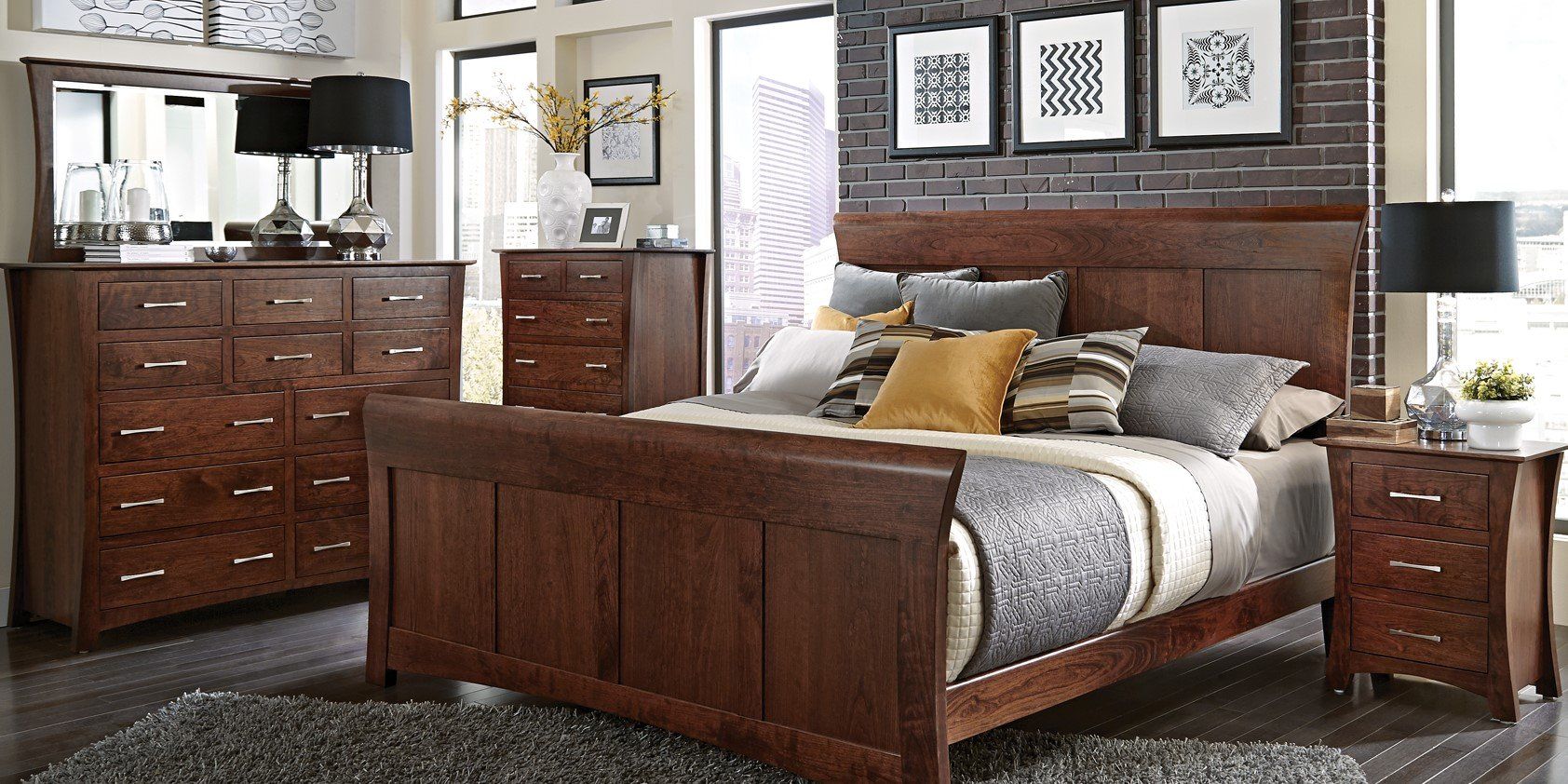 A bedroom with a bed , dresser , nightstand and mirror.