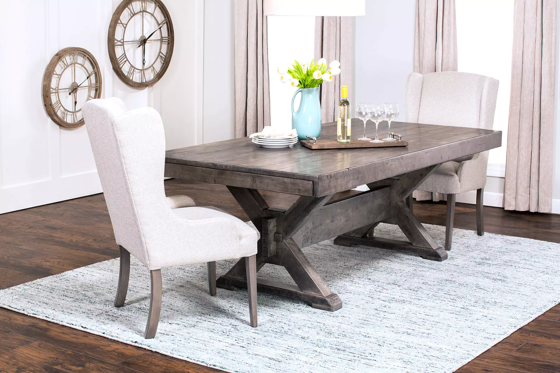 A dining room with a table and chairs and clocks on the wall.