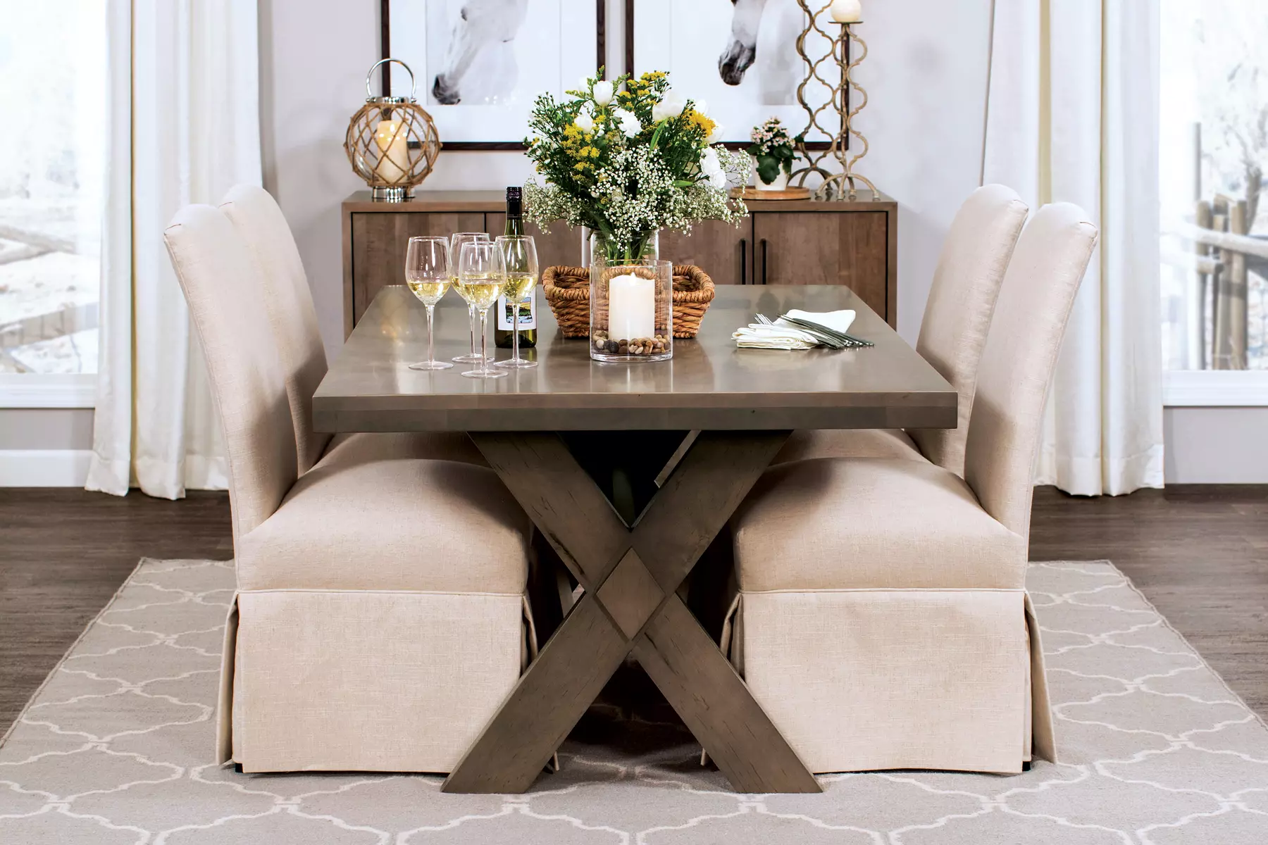 A dining room with a table and chairs and a vase of flowers on the table.
